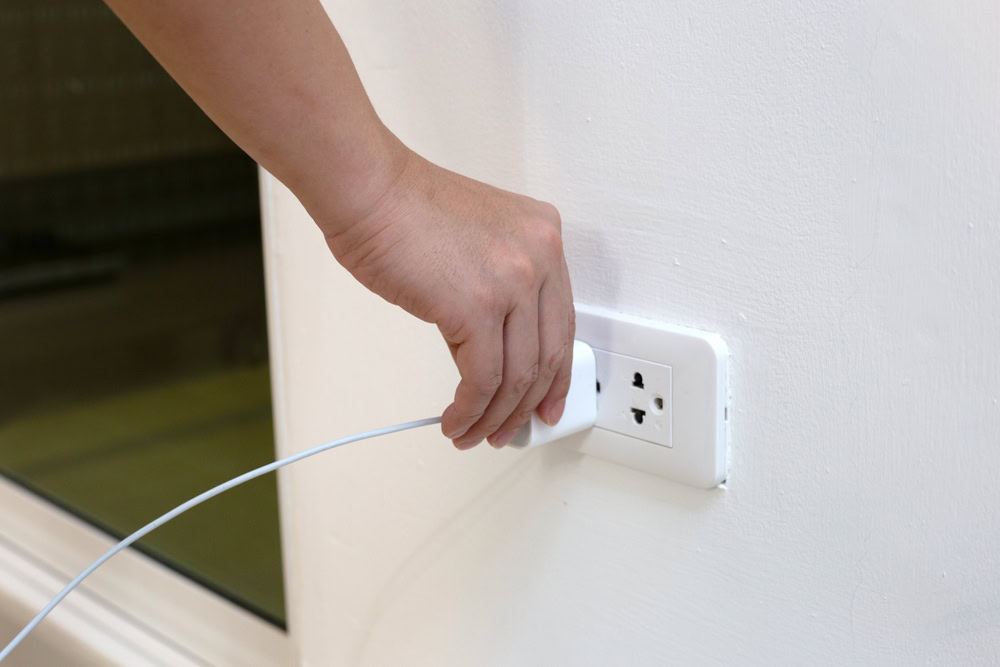 hand inserting phone charger to plug