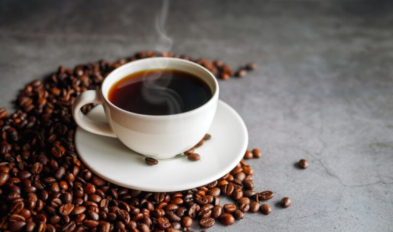 Coffee cup and coffee beans on gray background