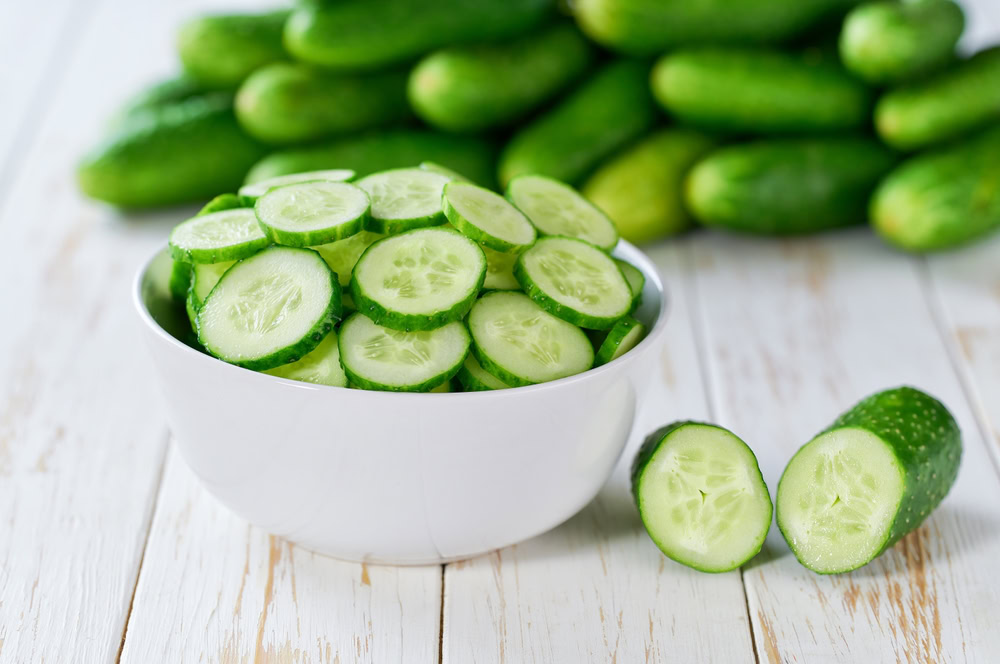 Organic cucumbers slices in a ceramic bowl on a light table
