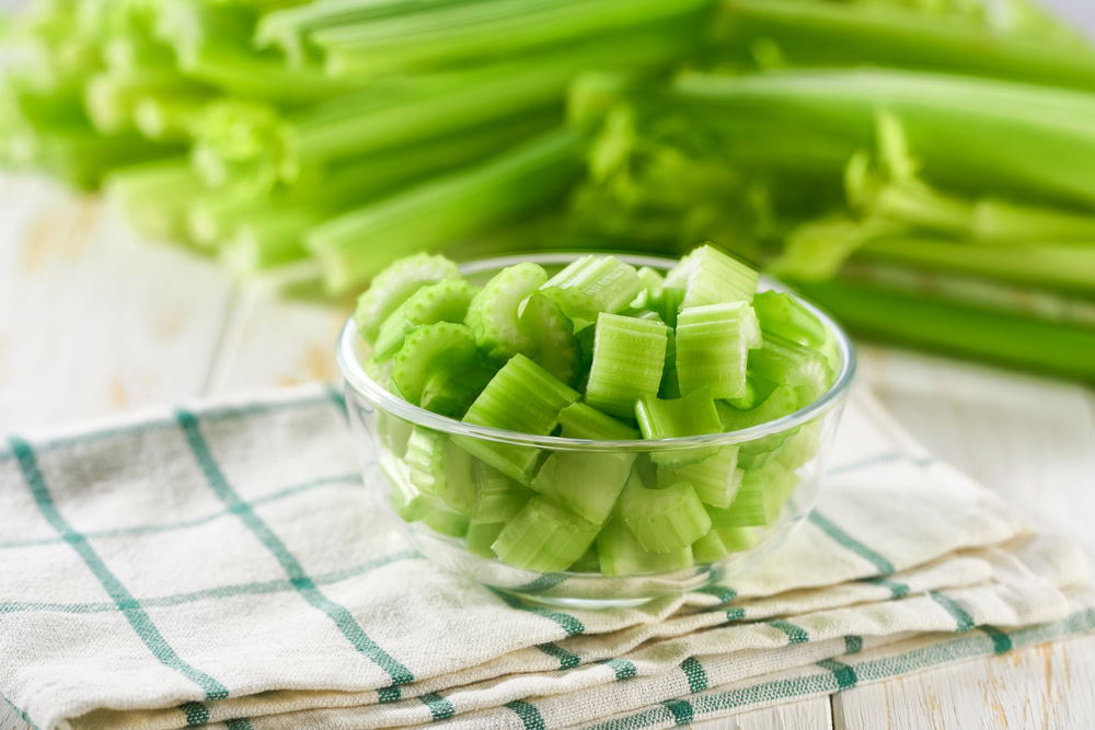 Sliced fresh celery or celery stalk on cutting wooden board