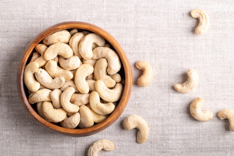 raw cashews in a wooden bowl on linen fabric