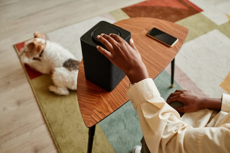 woman turning on the speaker with dog in the background