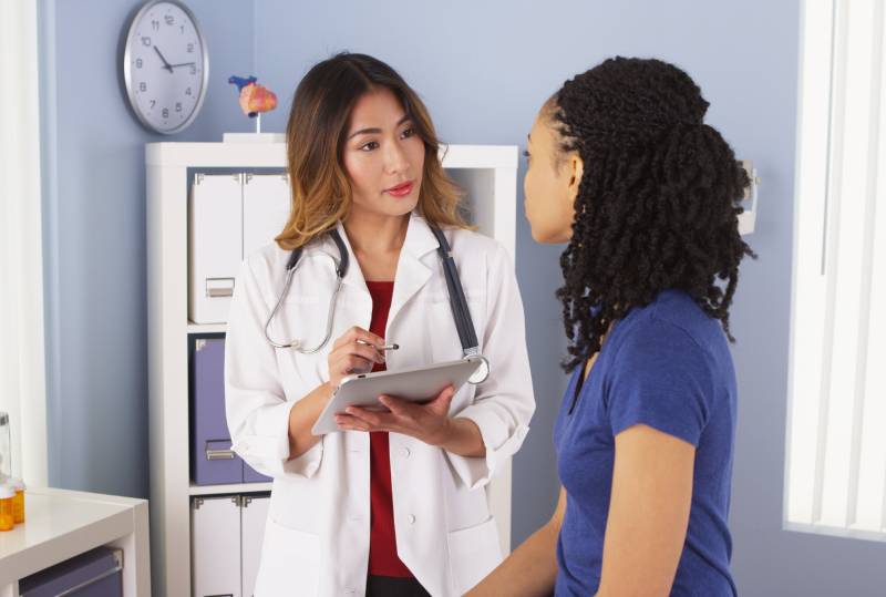 Asian physician explaining new prescription to black patient