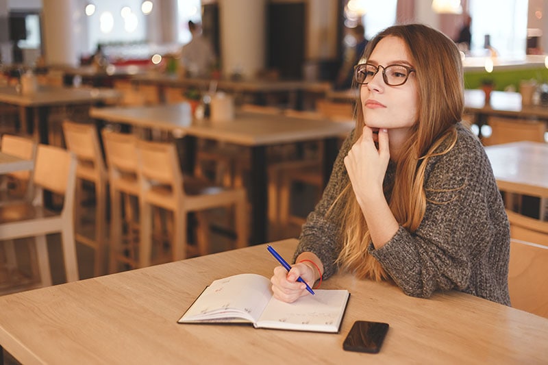 Business woman writing to do list in a cafe