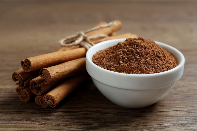 Cinnamon powder and sticks on wooden table