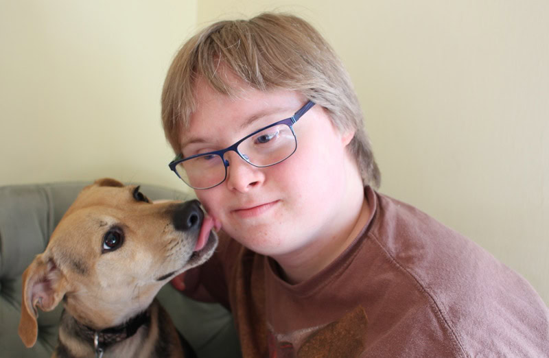 Cute dog licking a boy with Autism