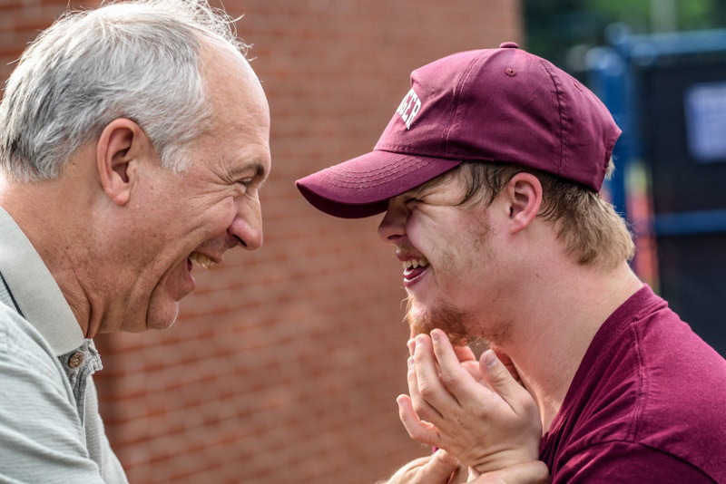 Old man and boy with autism smiling together