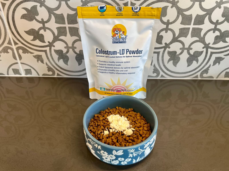 Super Pet Nutrition Colostrum-LD Powder - product packaging and a bowl of cat food with powder