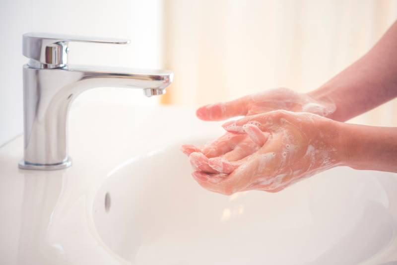 Washing hands with soap under the faucet with water