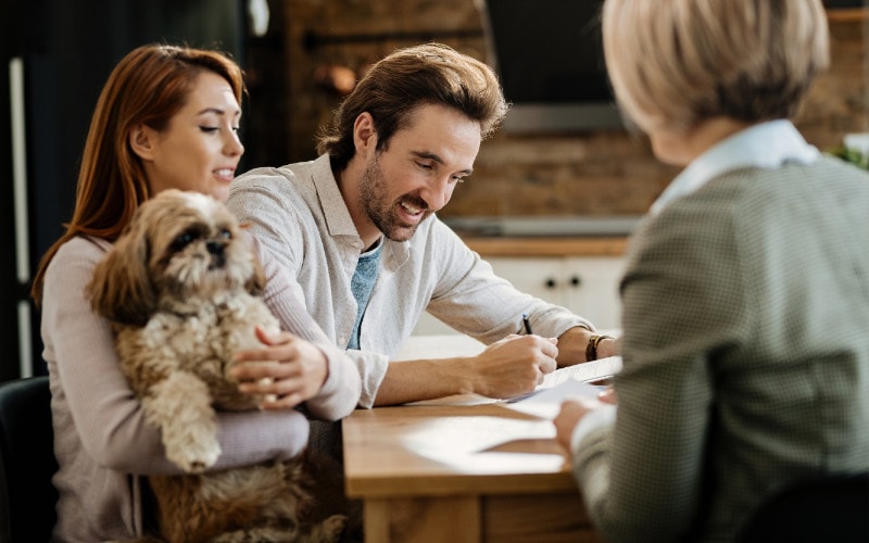 a couple with pet signing insurance contract