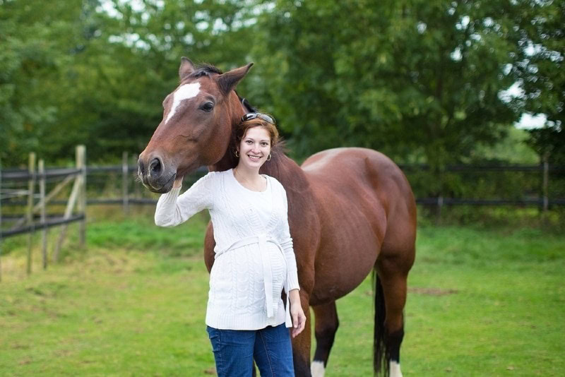a pregnant woman with a horse in the field