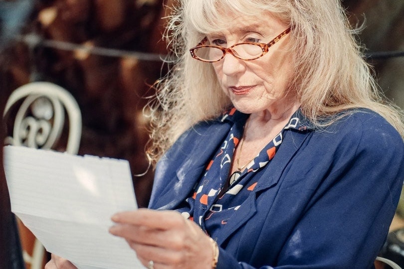 an elderly woman sitting while reading a letter