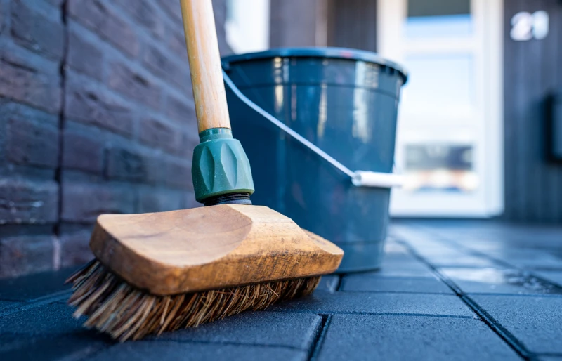 close up of outdoor broom brush and pail on concrete floor driveway