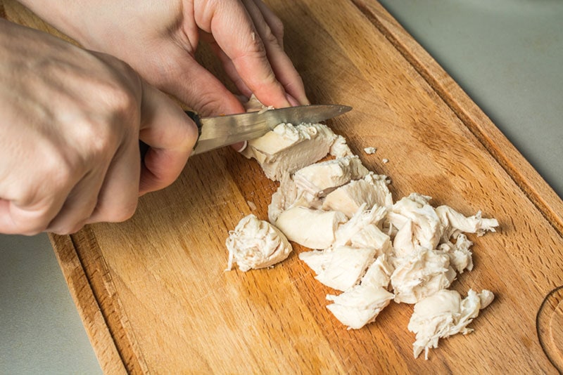 female-hands-cutting-boiled-chicken-breast-with-knife