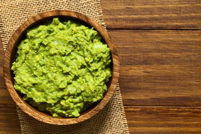 guacamole in wooden bowl, photographed overhead with natural light