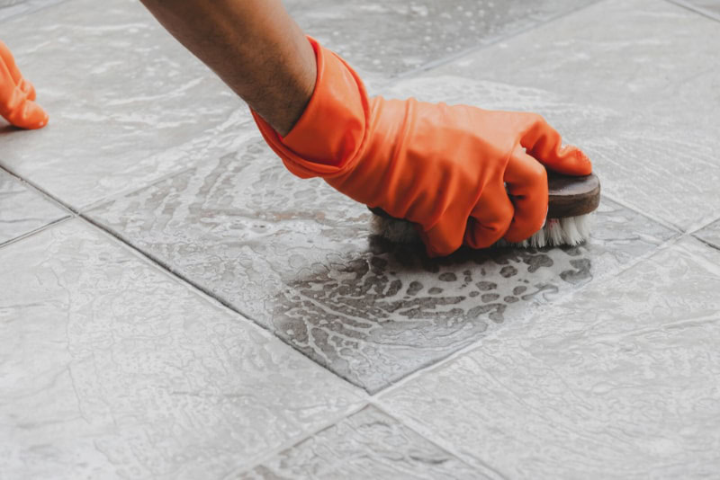 hand of a man with gloves scrubbing the floor