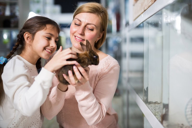 mother and daughter buying rabbit in pet shop