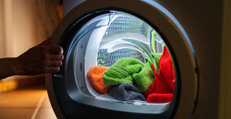 opens a washing machine or dryer at night with many colorful clean fresh hand towels