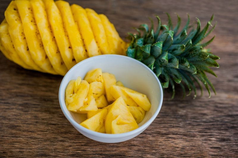 peeled pineapple and a bowl of pineapple slices