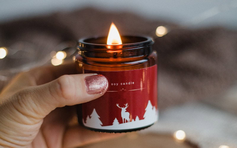person lighting a soy christmas candle