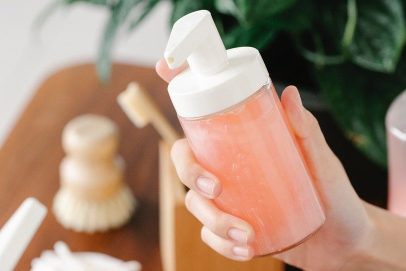 persons hand holding a hand soap bottle