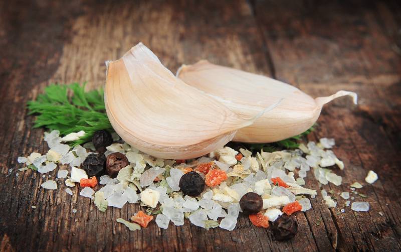 salt pile and pepper and garlic on wooden texture