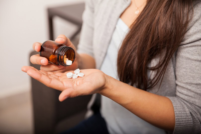 woman getting aspirin from bottle