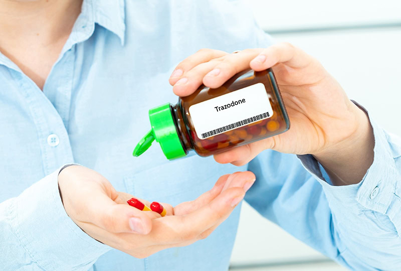 woman getting trazodone pills from the bottle