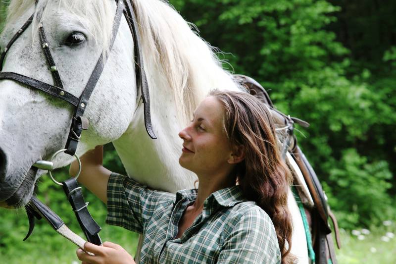 woman holding the white horse outdoors