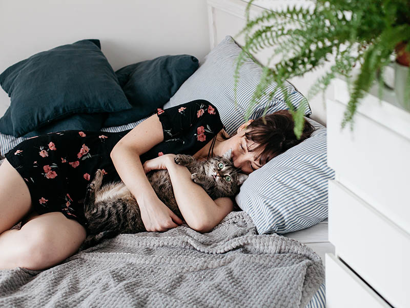 woman hugging a cat in bed