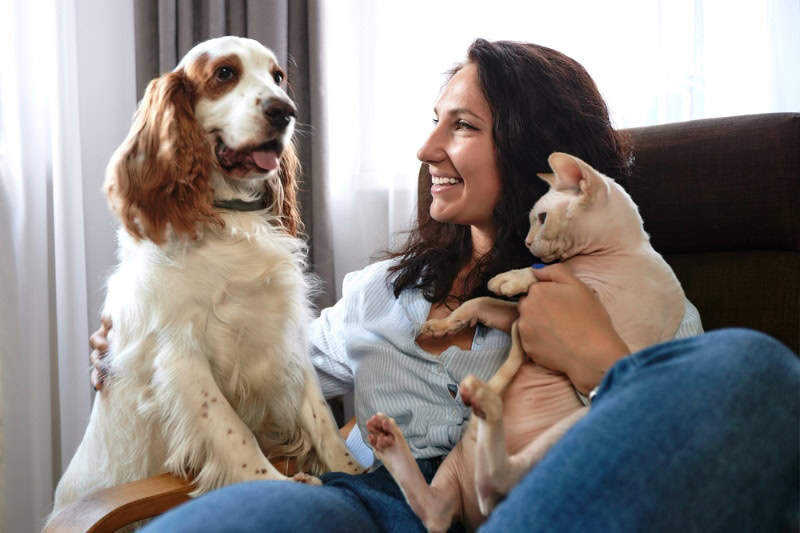 woman sitting on the sofa with her dog and cat