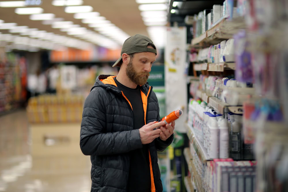 man checking contents or ingredients of a spray bottle before buying