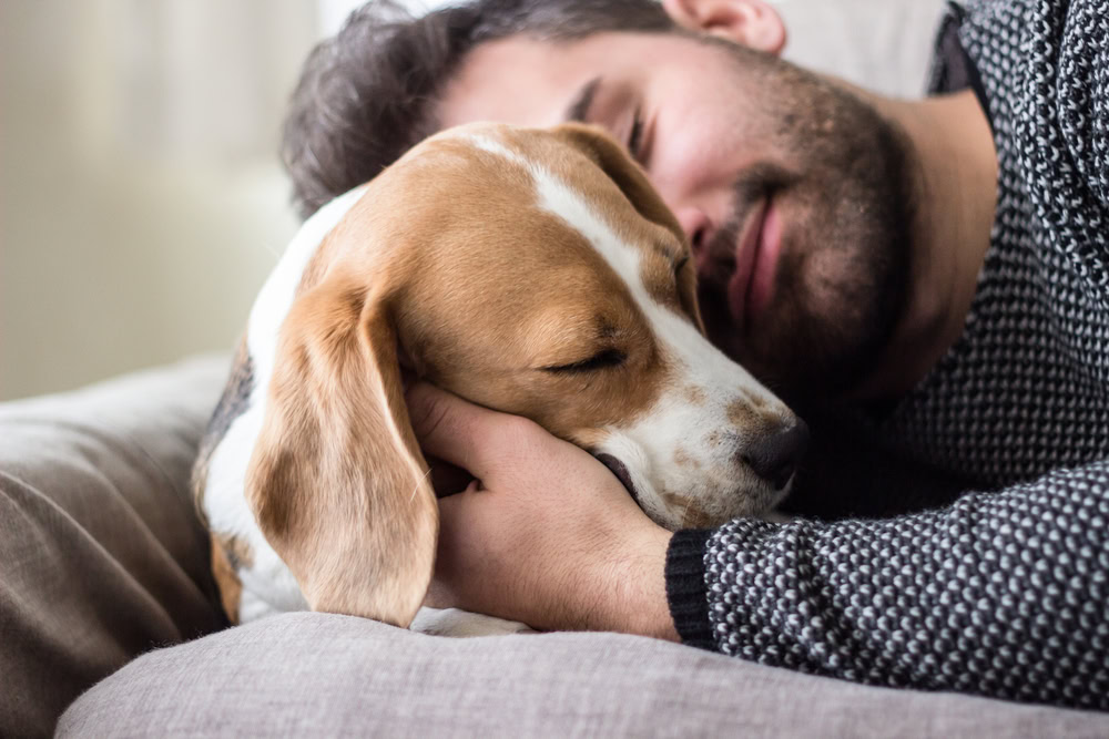 man cuddling with his dog
